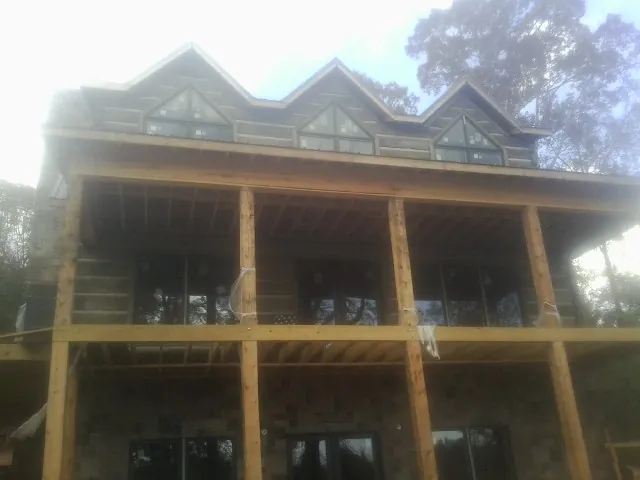 Dormers and porch framing on a large log home under construction — Roof Coating work by our crew in Lockwood